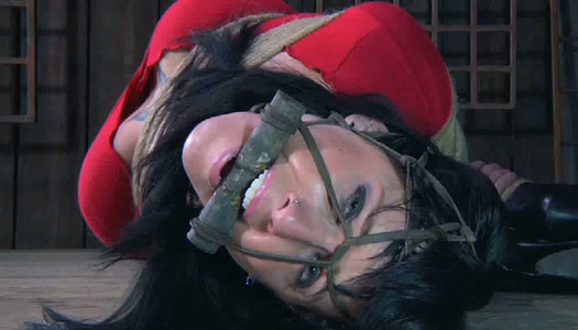 Pornobild Gefesselte großbrüstige Brünette muss mitten im Raum stehen bleiben