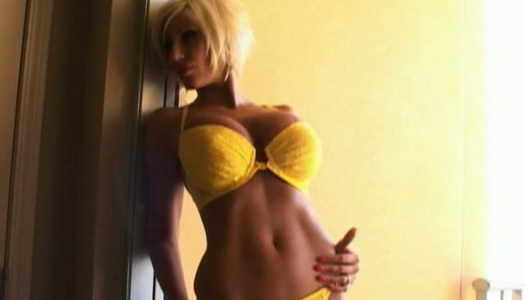 Kurzhaariger blonder Bimbo posiert in ihrem gelben Bikini im Türpfosten Porno Bilder